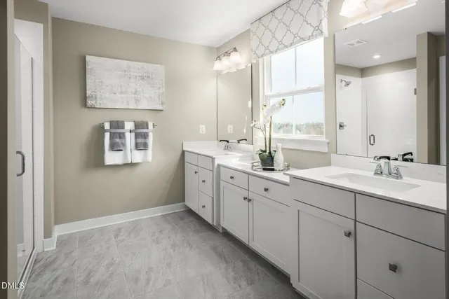a bathroom with double sink mirror and a window