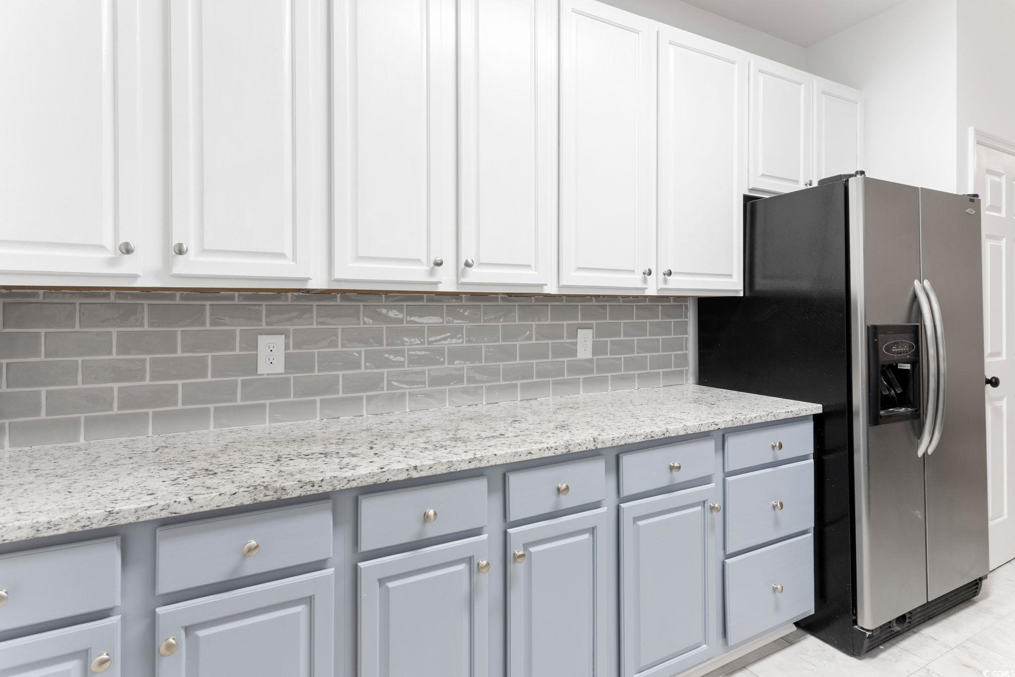 2321 Brick Drive Longs, SC 29568 - Photo 20 of 40 Kitchen featuring stainless steel fridge with ice dispenser, white cabinets, light stone counters, and backsplash