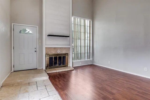 an empty room with wooden floor fireplace and windows