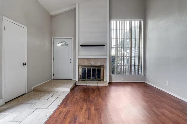 an empty room with wooden floor fireplace and windows