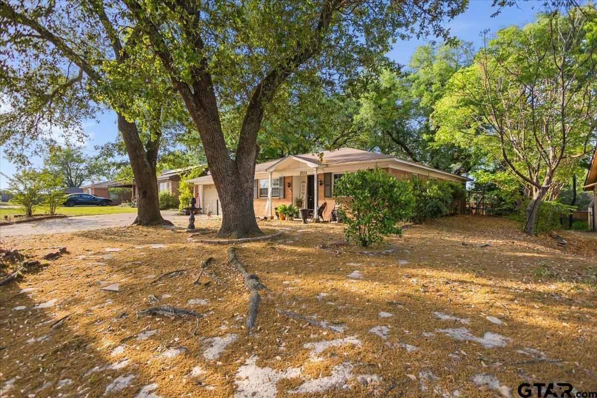 3211 Shady Trail Drive Tyler, TX 75702 - Photo 3 of 30 a backyard of a house with table and chairs under an umbrella