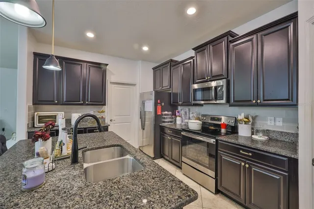 a kitchen with granite countertop a stove a sink and a microwave