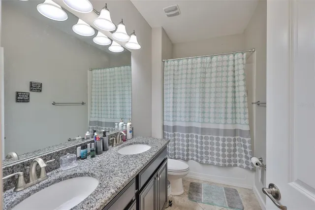 a bathroom with a granite countertop sink a toilet and a mirror