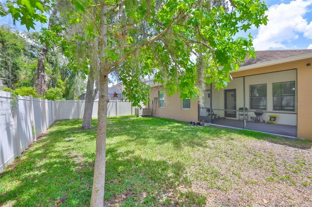 a view of a backyard with table and chairs and a large tree