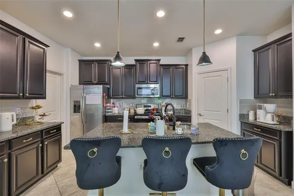 a kitchen with stainless steel appliances granite countertop a sink wooden cabinets and a refrigerator