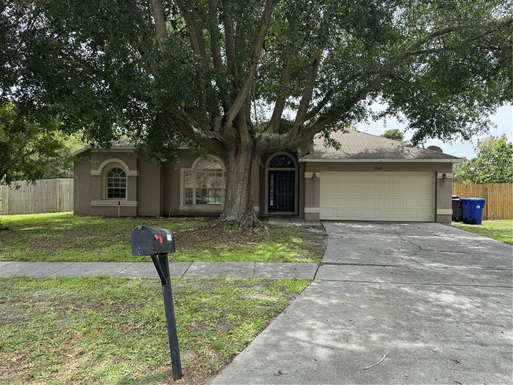 a front view of a house with a yard and large tree