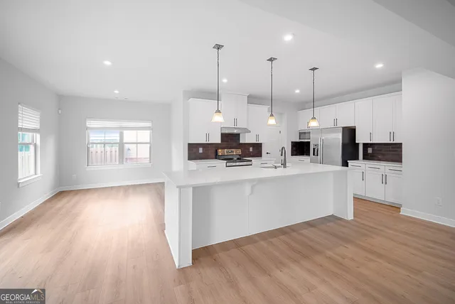 a kitchen with stainless steel appliances kitchen island wooden floors cabinets and window