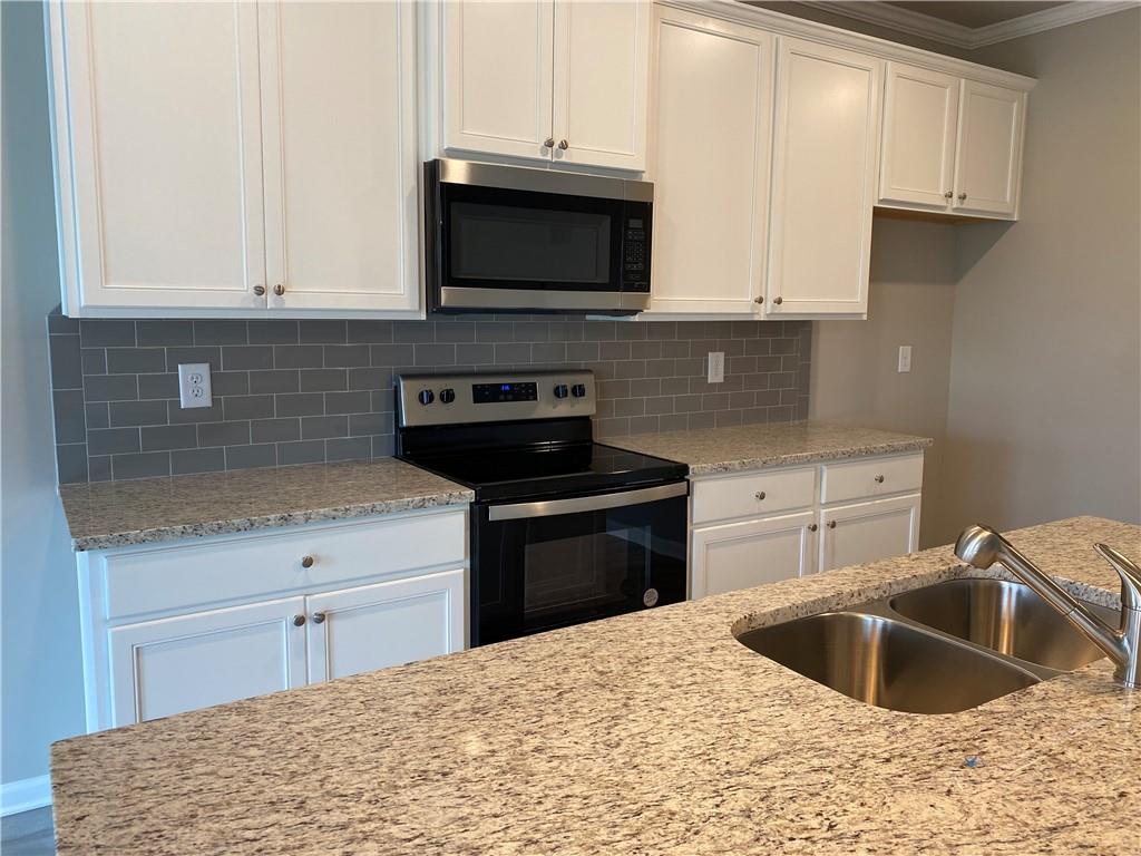 5282 Fox Den Road Oakwood, GA 30566 - Photo 12 of 14 a kitchen with stainless steel appliances granite countertop a sink stove and microwave