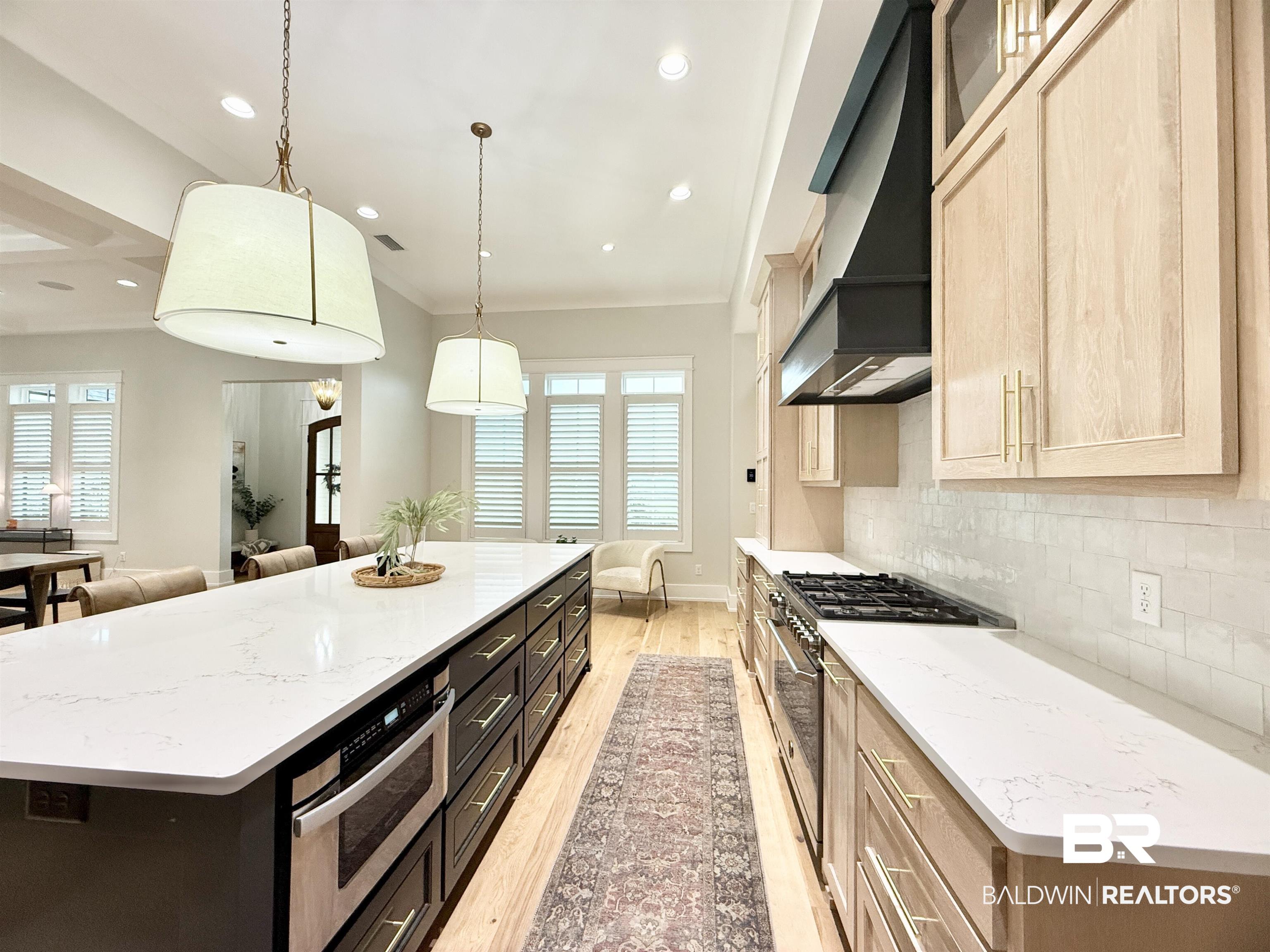 21767 Gallery Boulevard Fairhope, AL 36532 - Photo 14 of 74 Kitchen with a center island, light wood finished floors, wall chimney range hood, crown molding, and stainless steel stove