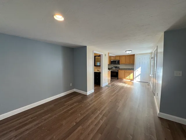 a view of a kitchen with a fridge and wooden floor