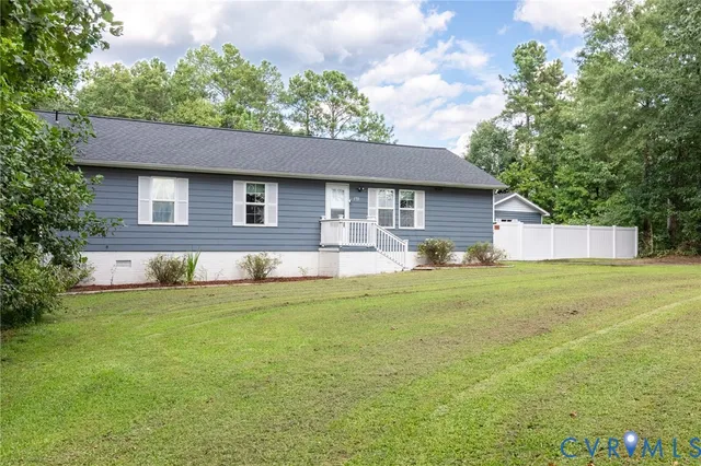 a front view of house with yard and trees in the background