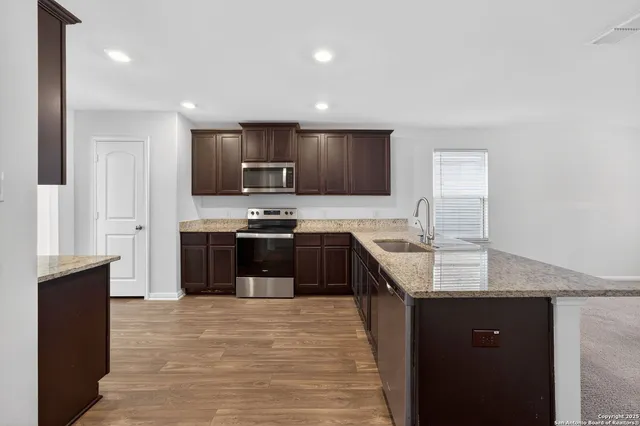 a large kitchen with stainless steel appliances granite countertop a stove a sink and a refrigerator
