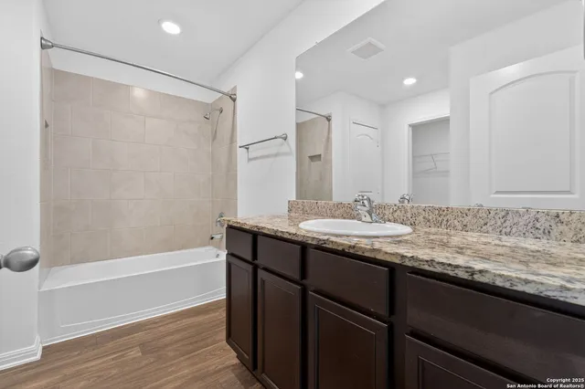 a bathroom with a granite countertop sink a mirror and a bathtub