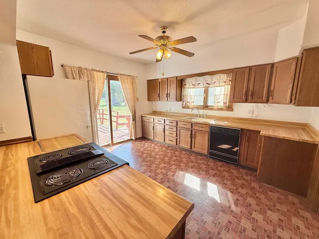 a living room with stainless steel appliances furniture a flat screen tv and a window