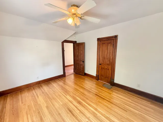 an empty room with wooden floor closet and windows