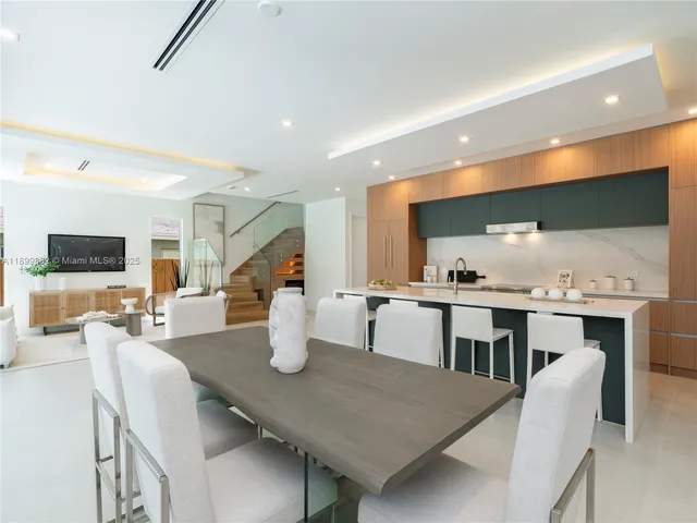 a dining room with wooden floor furniture and kitchen view