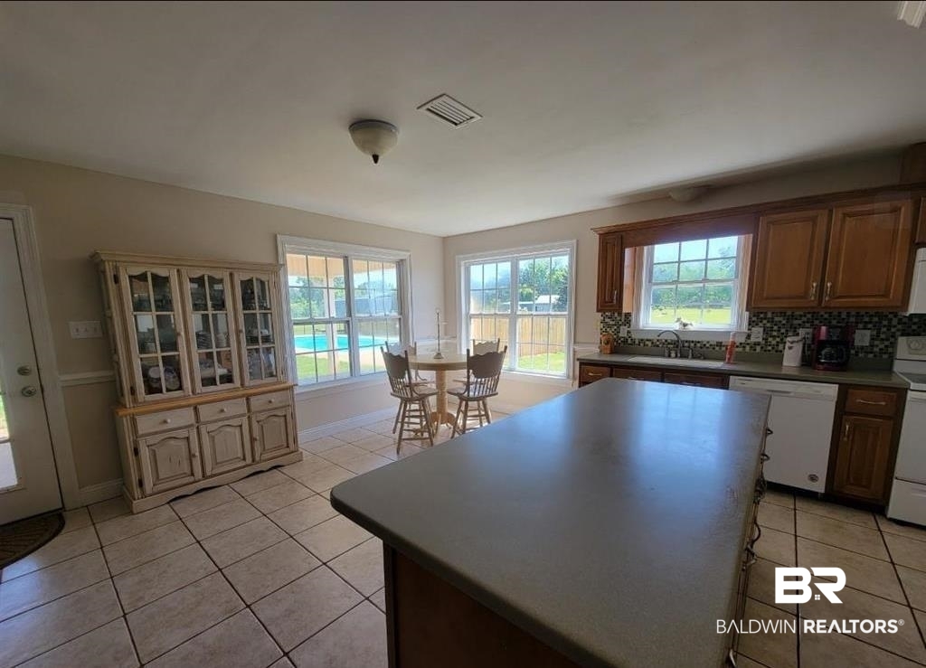 16311 Old Brady Road Bay Minette, AL 36507 - Photo 2 of 38 Kitchen featuring tile flooring, a central island with a solid surface countertop, wood cabinetry, and a tile backsplash
