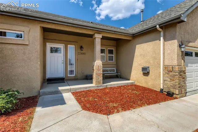 a living room with stainless steel appliances furniture a rug and a kitchen view