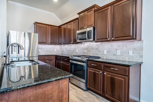 a kitchen with stainless steel appliances granite countertop a sink stove and microwave