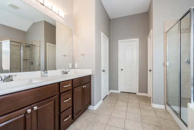 a spacious bathroom with a double vanity sink a large mirror and a shower