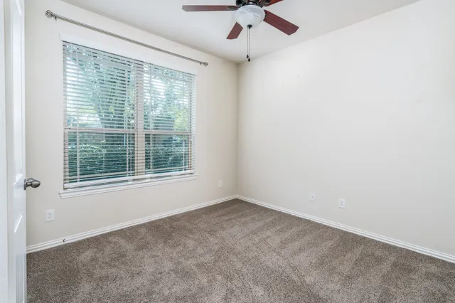 an empty room with a window and a fan