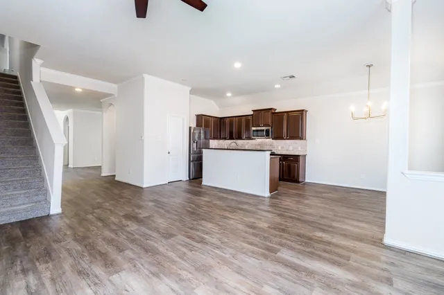 an empty room with wooden floor and a kitchen