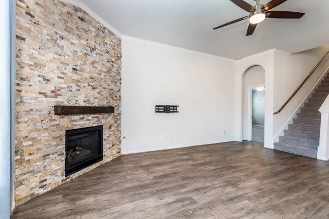 a view of a livingroom with wooden floor a fireplace and a ceiling fan