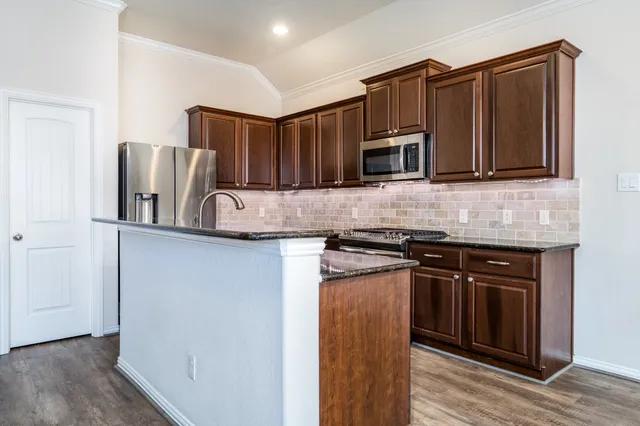 a kitchen with stainless steel appliances granite countertop a stove microwave and refrigerator