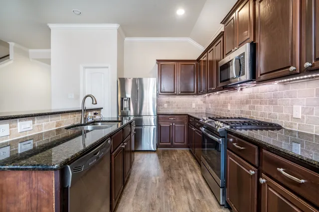 a kitchen with stainless steel appliances granite countertop a stove top oven a sink and dishwasher