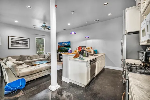 a kitchen that has a lot of white cabinets and stainless steel appliances