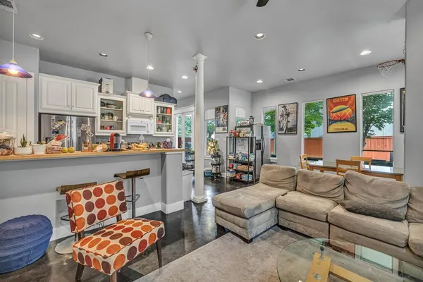 a living room with furniture kitchen view and a large window