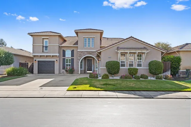 a front view of a house with a yard and potted plants