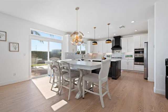 a kitchen with stainless steel appliances kitchen island granite countertop a table chairs and a refrigerator
