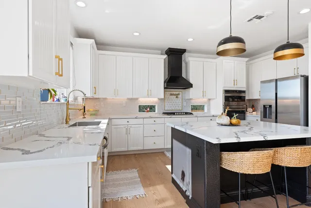 a kitchen with stainless steel appliances granite countertop a sink a stove and a refrigerator