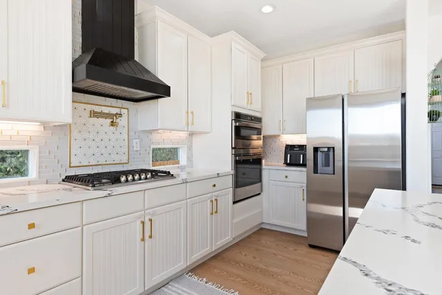 a kitchen with stainless steel appliances granite countertop a sink a stove a refrigerator and island