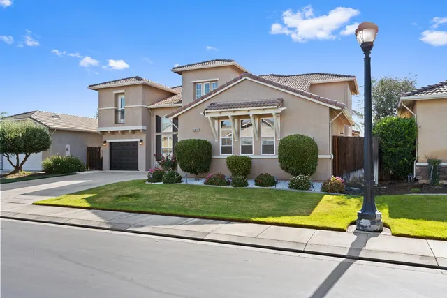 a view of a white house with a big yard and plants