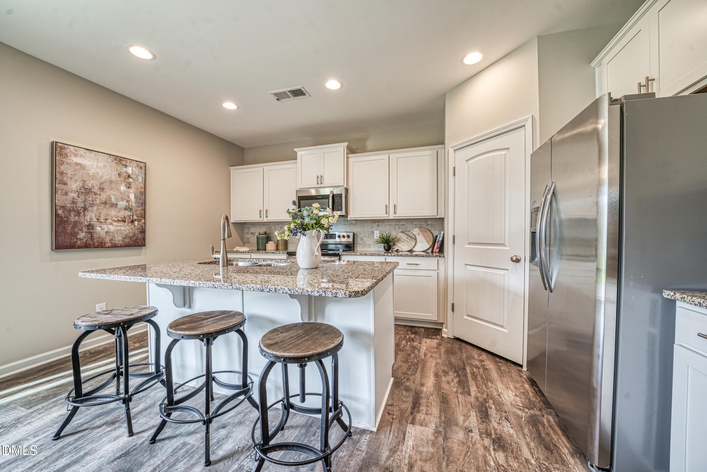 2304 Broad Street Durham, NC 27704 - Photo 5 of 39 a kitchen with stainless steel appliances a refrigerator a stove a sink and a dining table with wooden floor