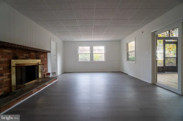 an empty room with wooden floor fireplace and windows