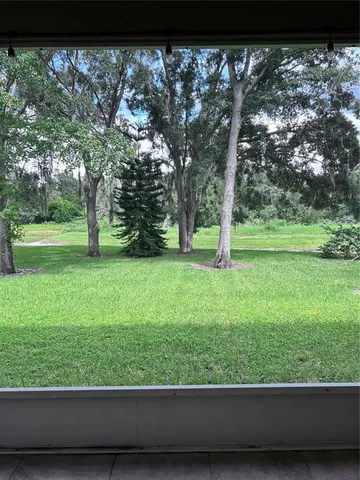 a view of green field with trees in the background