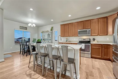 a kitchen with stainless steel appliances kitchen island granite countertop a table chairs and a refrigerator