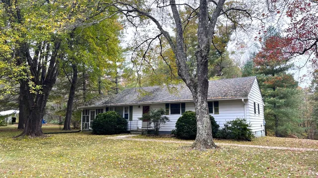 a view of a house with a yard and large tree