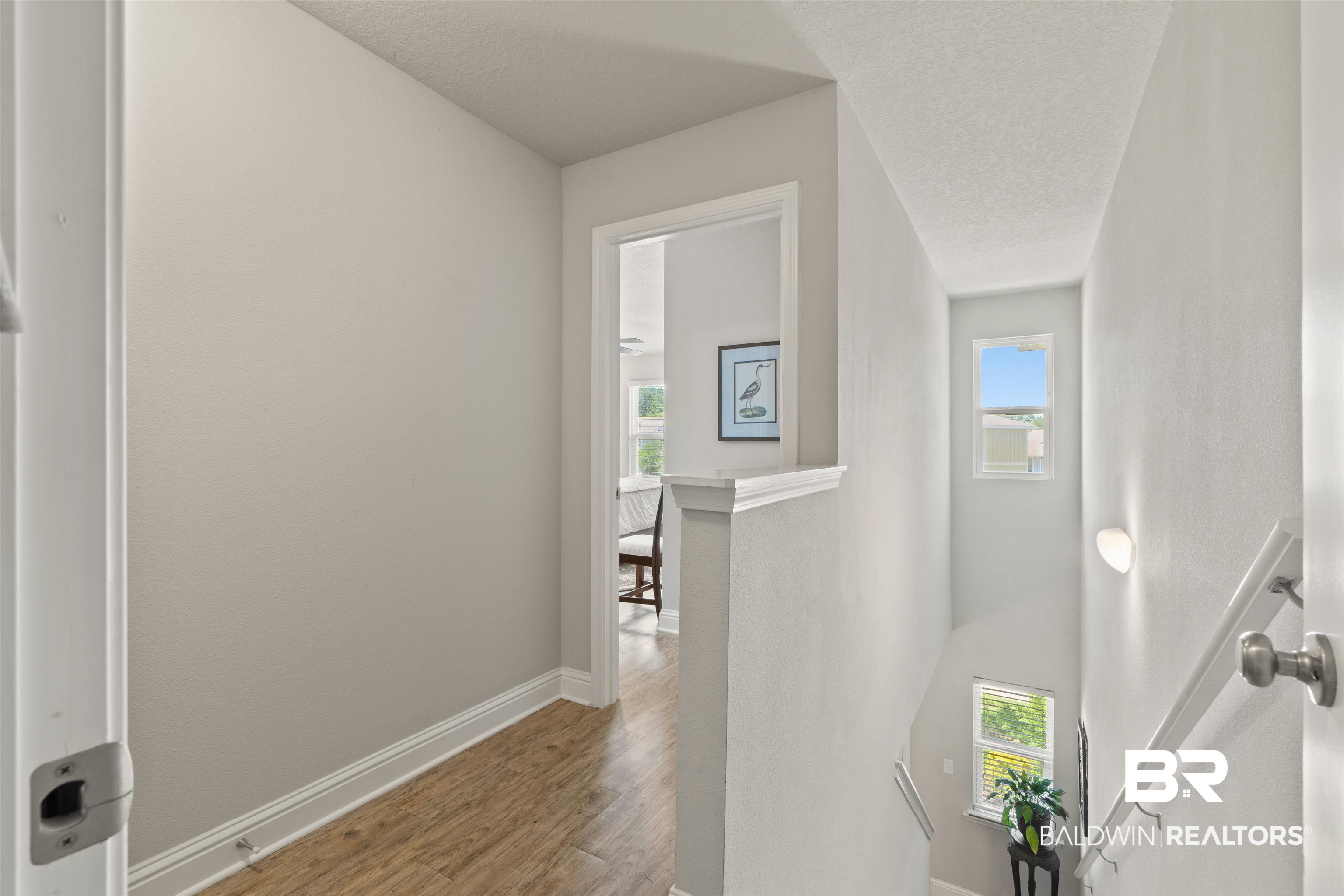 25806 Pollard Road, Unit 6 Daphne, AL 36526 - Photo 14 of 38 Upper-level hallway with wood-finish flooring, white baseboards, and a doorway leading to an interior room