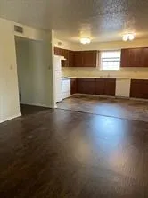 a view of kitchen and empty room with wooden floor