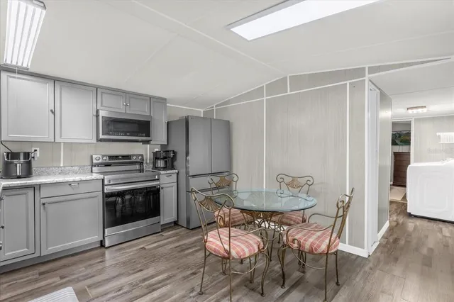 a kitchen with stainless steel appliances a dining table chairs stove and refrigerator