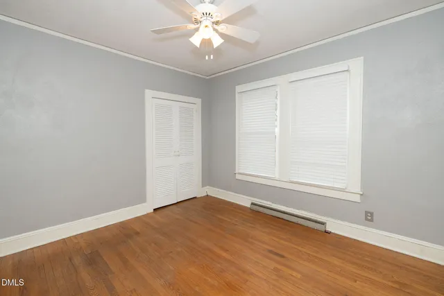 an empty room with wooden floor fan and windows