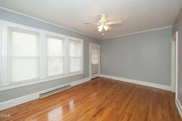 a view of an empty room with wooden floor and a window