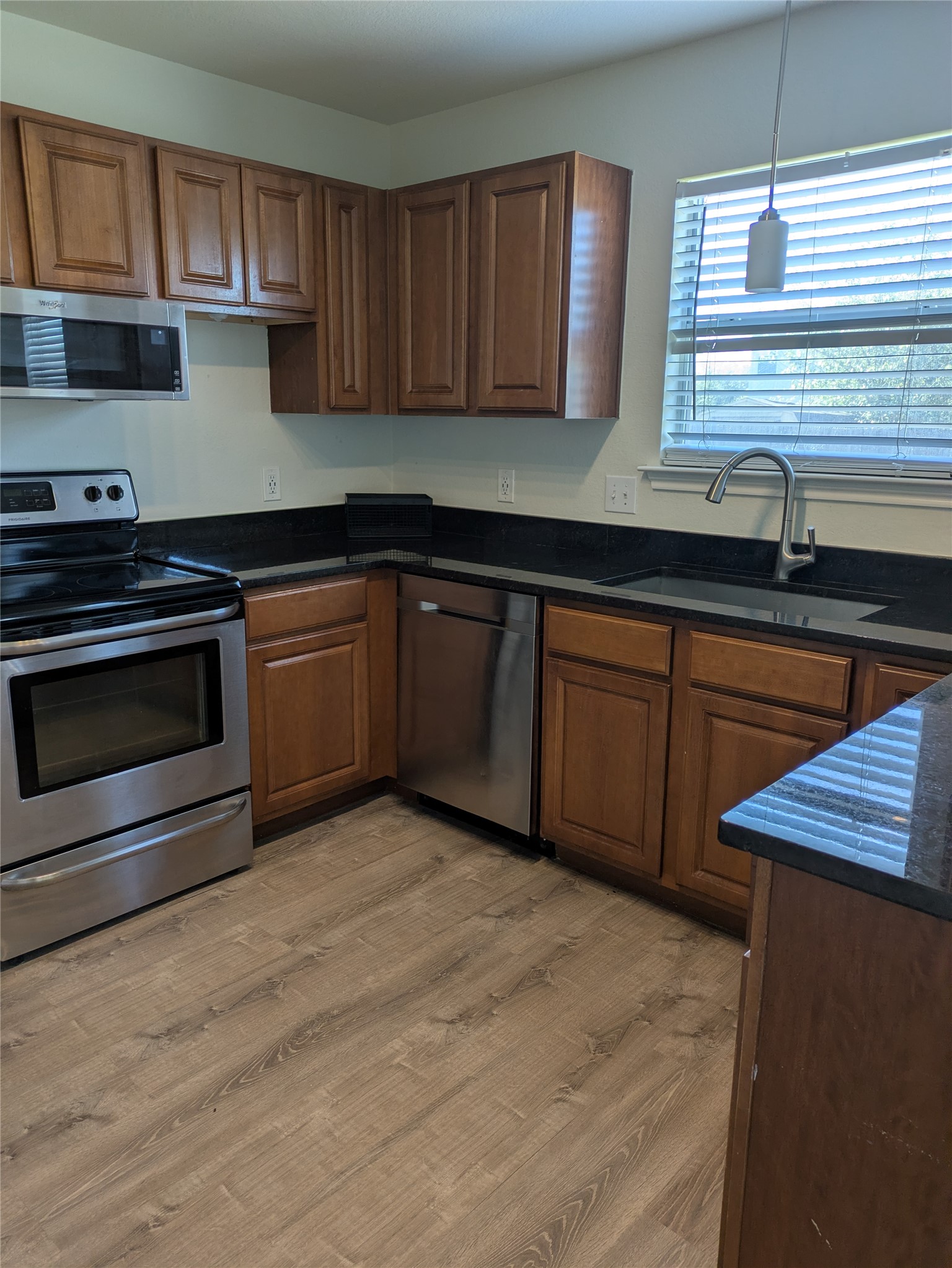 209 Phillips Street Hutto, TX 78634 - Photo 2 of 11 a kitchen with granite countertop wood cabinets stainless steel appliances and a sink