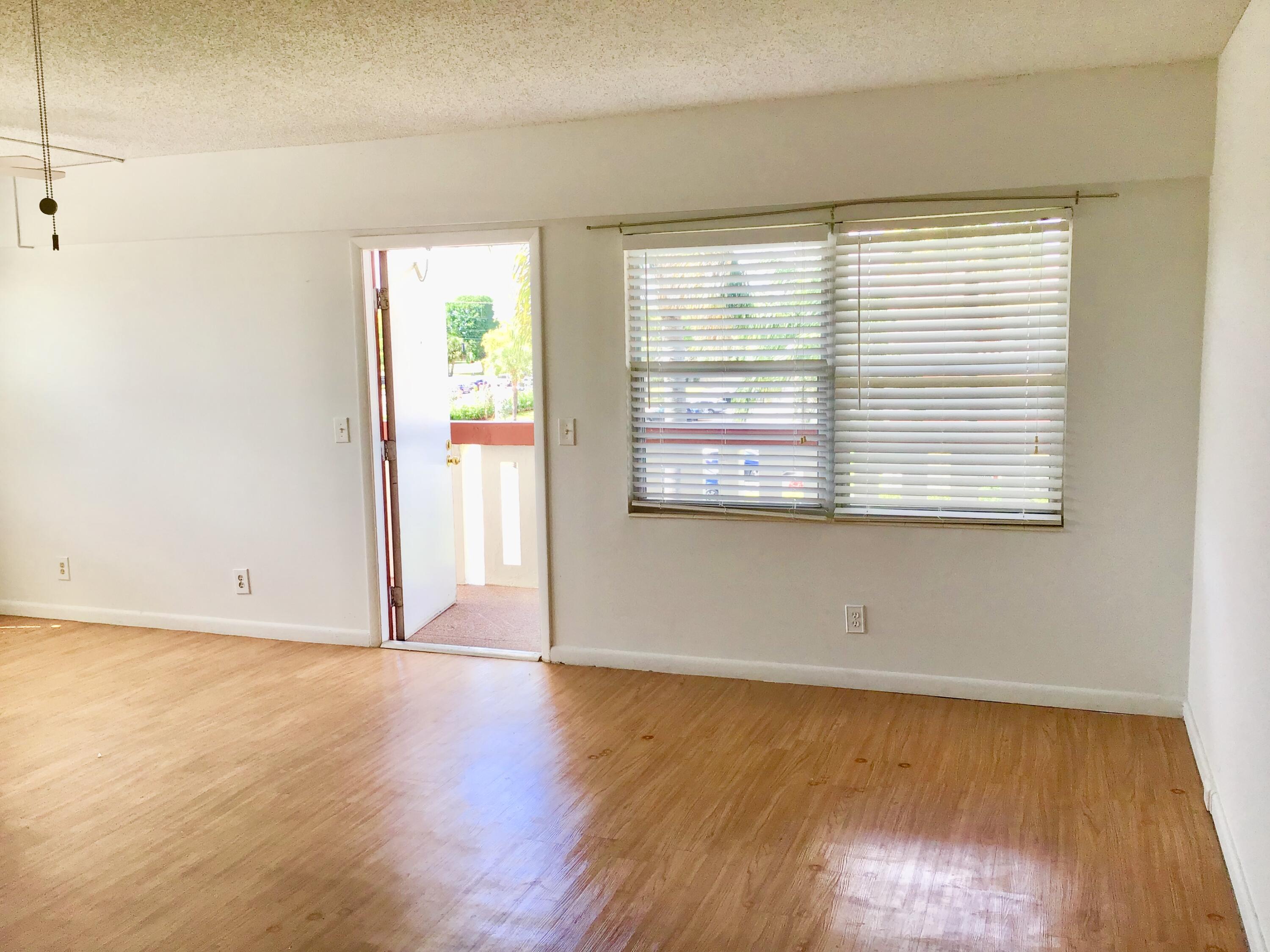 84 Brighton B, Unit 84 Boca Raton, FL 33434 - Photo 8 of 28 a view of an empty room with wooden floor and a window