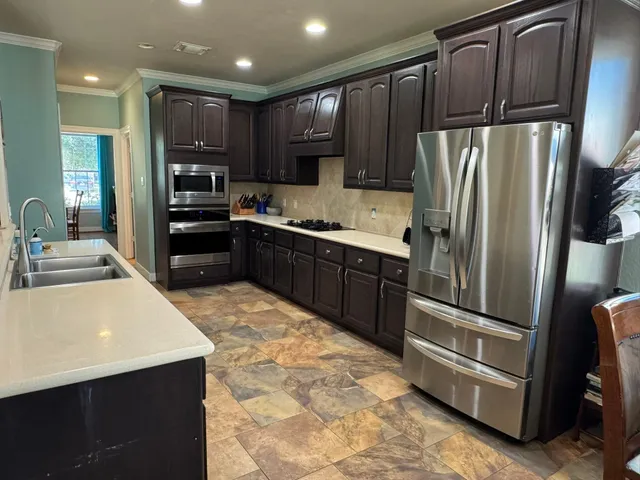 a kitchen with stainless steel appliances wooden cabinets a sink and a refrigerator