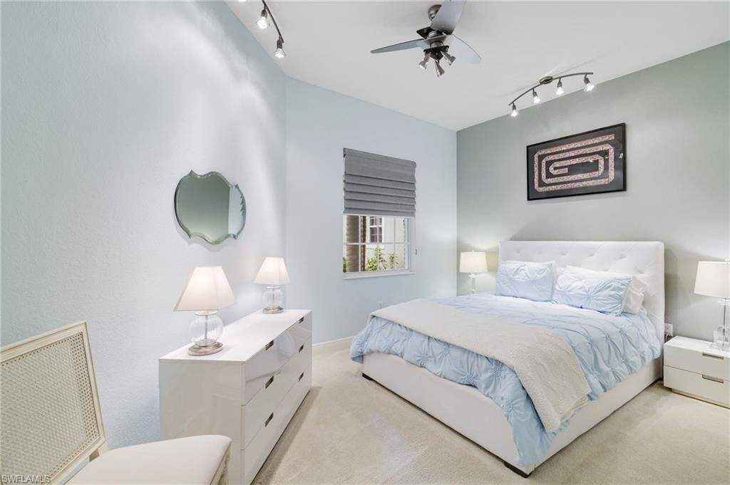 19670 Marino Lake Circle, Unit 2502 Miromar Lakes, FL 33913 - Photo 11 of 40 a bedroom with a white bed and a chandelier